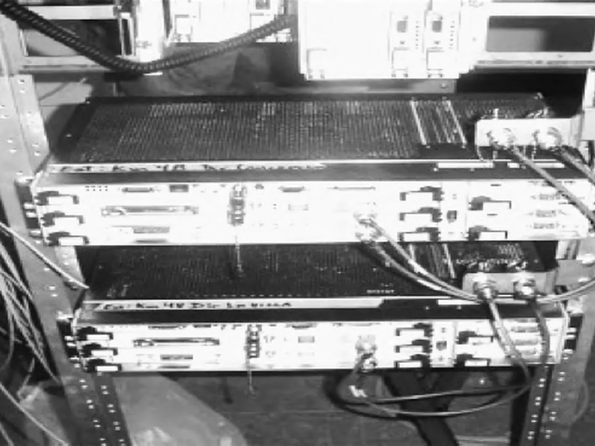 Rack de telecomunicaciones con dos equipos multiplexores y sus cables coaxiales, en blanco y negro