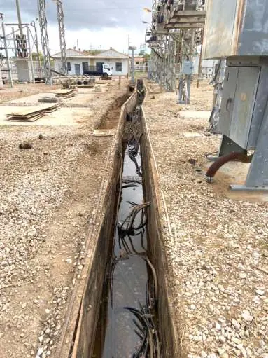 Trinchera vieja del patio de 24 kV con agua y cables, antes