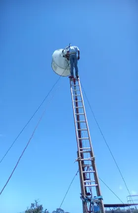 Técnico en el mástil arriostrado, con la antena instalada