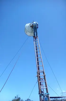 Técnico en el mástil arriostrado, con la antena instalada