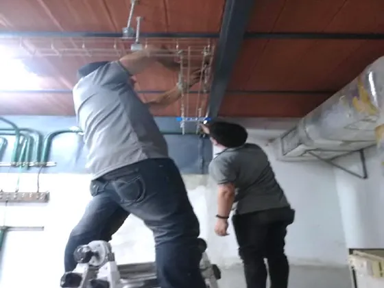 Dos técnicos de Favinca instalando bandeja portacables bajo techo